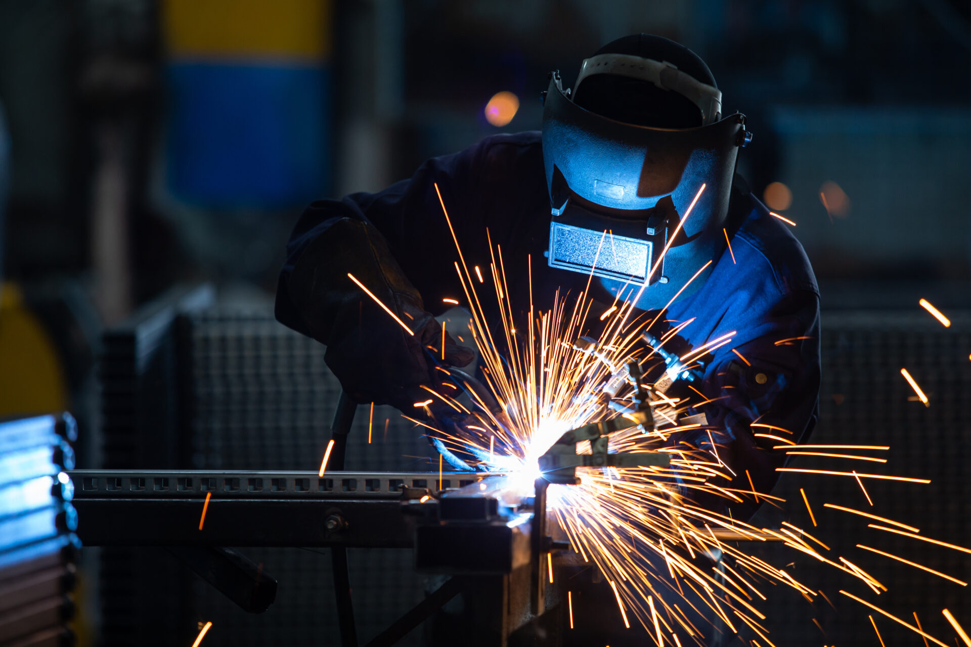 Workers wearing industrial uniforms and Welded Iron Mask at Steel welding plants, industrial safety first concept.